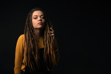 Portrait of a young girl with dreads on black background. Studio shoot.