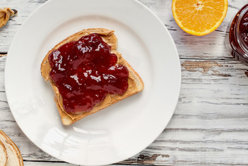 Top view of open face homemade peanut butter and strawberry Jelly sandwich on oat bread, over a...