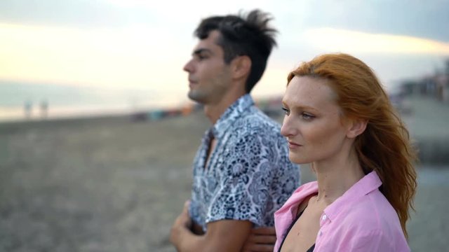 Young pensive couple standing on the beach