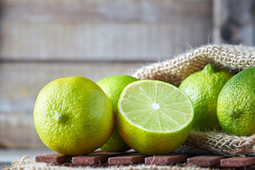 Fresh ripe organic limes on wooden background. Copy space