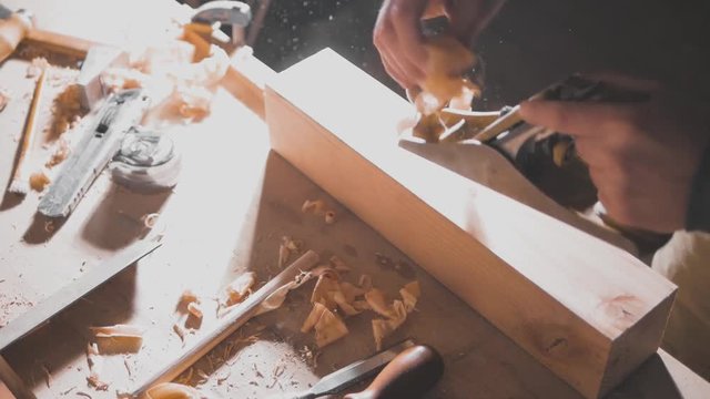 carpenter planes the workpiece with a plane, chips and dust fly, slow motion