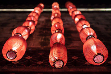 Group of red chinese lanterns hanging on a wall illuminated at night for the chinese new year