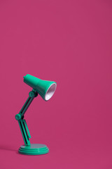 Vintage green desk lamp turned off on a bright pink background.  Landscape orientation with a left...