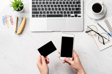 A woman is doing a online purchase, mock up credit card and mobile cellphone on office desk isolated on beautiful fashion marble background, copy space, topview, flatlay, closeup