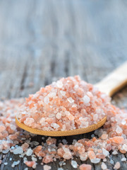 Fototapeta na wymiar Pink Himalayan salt in spoon on wooden background. Healthy spice closeup