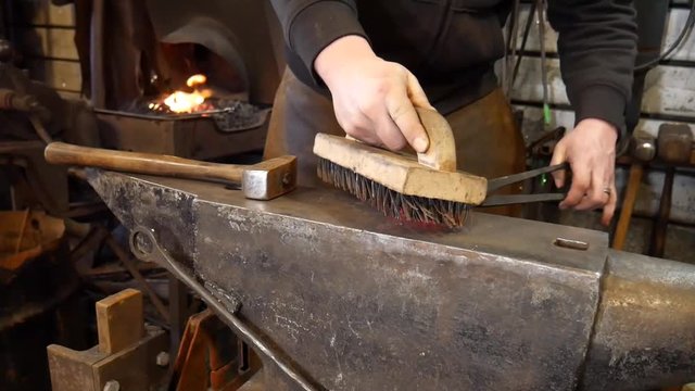 Blacksmith Cleaning Metal with Wire Brush to Complete Hand Forged Heart Blacksmith Project