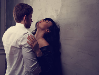 Sexy couple portrait. Man in white shirt kissing his sensual beautiful girlfriend in neck with much...