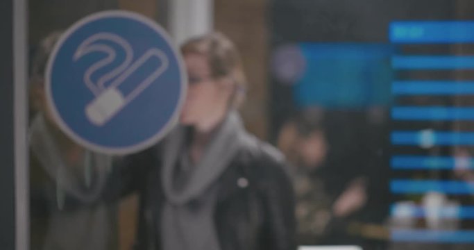 Young girl at airport comes into smoking room and smokes an electronic hookah
