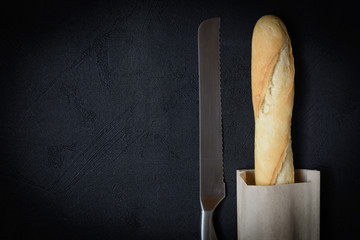 Fresh french roll baked crunchy baguette bread on dark background. Closeup of crust of bread food background. Top view. Natural lighting