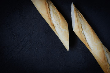 Fresh french roll baked crunchy baguette bread on dark background. Closeup of crust of bread food...