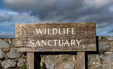 Fototapeta premium Wildlife sactuary sign outside stone wall barrier