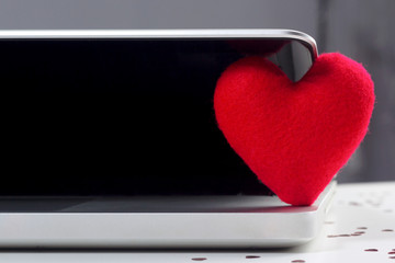 14 February Valentine's Day with red heart shaped fabrics on working table with laptop