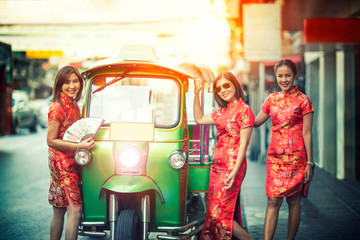 Obraz premium three asian woman wearing chinese traditon clothes standing beside tuktuk in yaowaratch road chinatown bangkok thailand