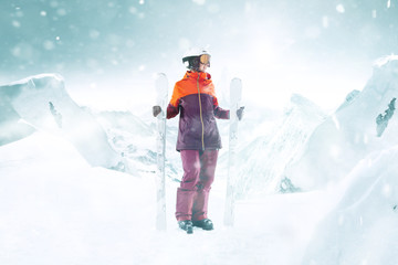 Female skier standing with skies in one hand on beautiful mountain landscape background. Winter, ski, snow, vacation, sport, leisure, lifestyle concept