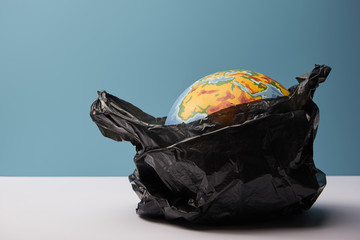 globe in black polyethylene bag on white table and blue background