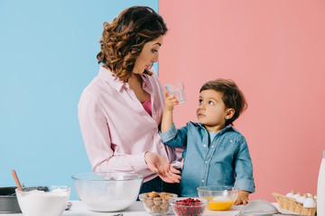 cute little boy showing mother empty glass on bicolor background