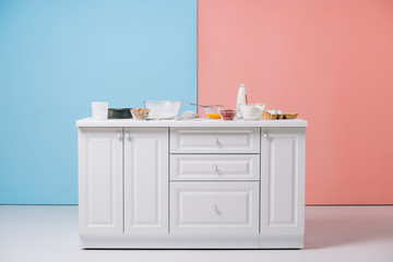 white kitchen table with various cooking utensils and products on bicolor background