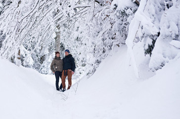 Smiling couple standing on a snow covered path while hiking