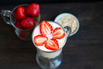 Milk shake with strawberries or breakfast with muesli and yogurt and berries on a dark background