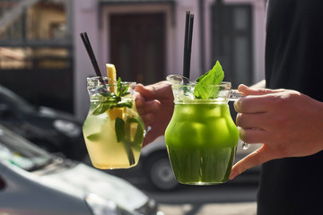 Two lemonade in the hands of the man. fresh cucumber and lemon drinks.