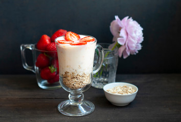 Milk shake with strawberries or breakfast with muesli and yogurt and berries on a dark background