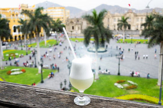 Pisco Sour Homemade Cocktail With The Background Of The Main Square Of Lima - Peru