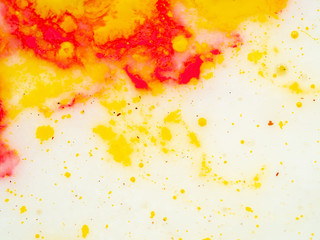 Splashes of red and yellow paint, abstract background. Close up shot. Blurred background. Abstract pattern on white background. Colourful splashes of yellow and red paint. Macro shot