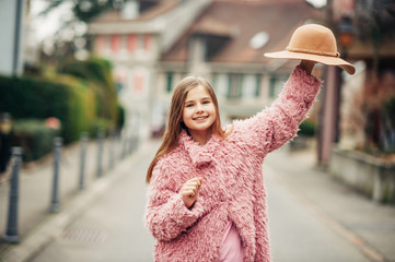 Outdoor fashion portrait of young girl wearing pink faux fur coat, street style