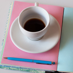 A Cup of black coffee on an open diary. Diary for a girl