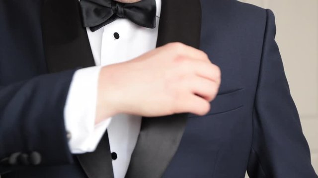 Man adjusting pocket squar from tux slow