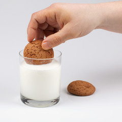 Hand dipping oatmeal cookies in milk