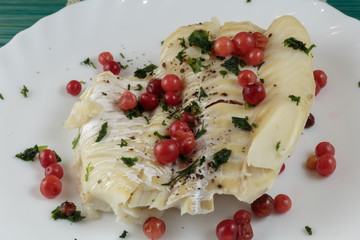 Boiled cod fillet with berries, herbs and spices on a plate close-up. Dietary healthy food.