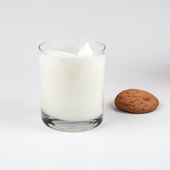 A glass of milk and oatmeal cookies on a light background. Healthy breakfast. Milk spray