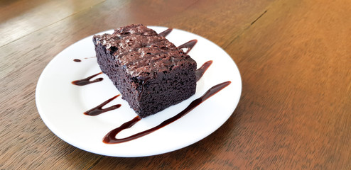 Chocolate brownie in white plate on wood table background