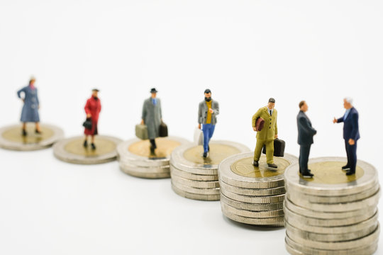 Miniature business man model on increase of stacking coins money with white background. Income and economic inequality concept with copy space and business concept. -Image.