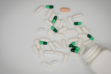 Top view of assorted Pharmaceutical medicine pills, capsules and tablets with white bottle on white background. Copy space for add text - Image