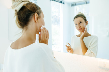 Obraz na płótnie Canvas Woman applying face cream in bathroom
