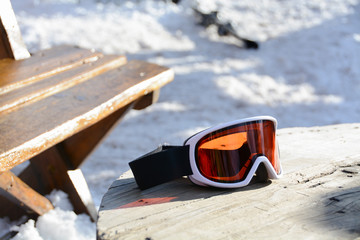 Skiing glasses with orange glass on a wooden table after skiing. A break after the skiing. Tea time...