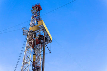 Fototapeta na wymiar Oil and Gas Drilling Rig onshore dessert with dramatic cloudscape. Oil drilling rig operation on the oil platform in oil and gas industry. Land drilling rig blue sky