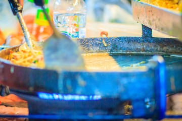 Close up hand of vendor during cooking for Padthai, the original Thai Fried Noodle, stir-fried noodle with shrimp and egg commonly served as a street food popular in Thailand