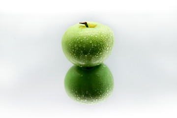 Green Apple in water drops on white background with reflection