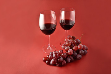 Red wine with grapes stock images. Two glasses of red wine. Red wine on a red background