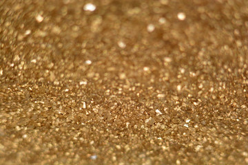 defocused golden glitter background with bokeh effects, golden glitter sand texture with light reflections