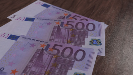 Few five hundred euro banknotes on the wooden floor. 500 european cash currency 3D illustration, depth of field.