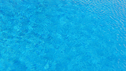 Fototapeta na wymiar Swimming pool water background with texture of water surface with ripple effect, concept for summer vacation or spa, relaxation or working from anywhere, natural pattern with copy space