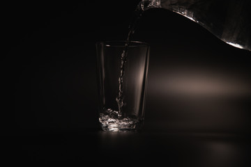 Water is poured into a transparent glass on a dark background