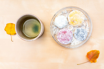 Green tea cup and mochi rice cake Japanese dessert wagashi colorful daifuku autumn leaves on table color and flat top view