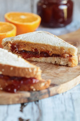 Homemade sliced peanut butter and jelly sandwich on oat bread, over a rustic wooden background ready for lunch. Selective focus with on center of sandwich with blurred foreground and background.