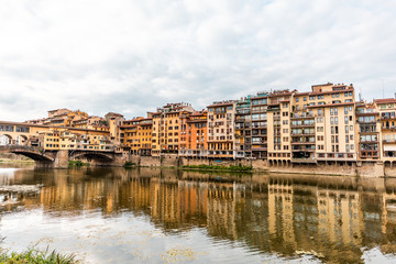 Fototapeta na wymiar Florence, Italy Firenze orange yellow colorful building on Ponte Vecchio by Arno river during summer morning in Tuscany with nobody and reflection