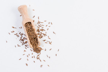 Caraway seeds in wooden scoop isolated on white background. Closeup.